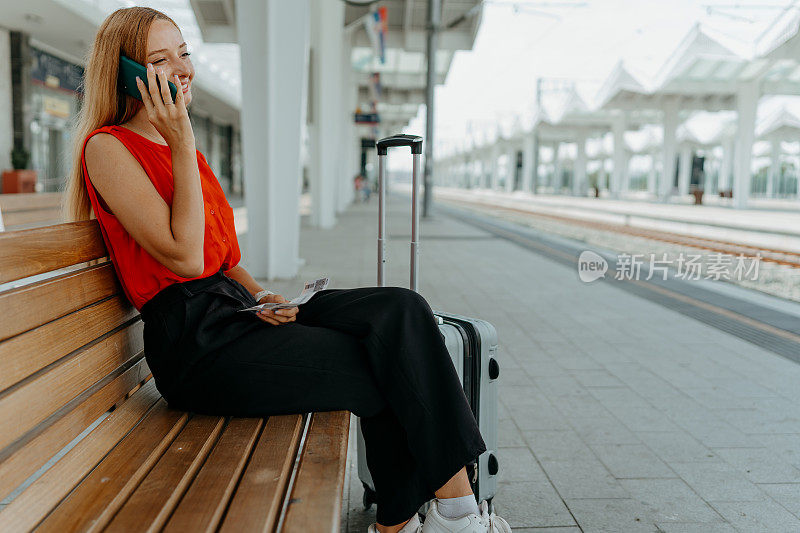 火车站长凳上的年轻女子，全神贯注地玩手机