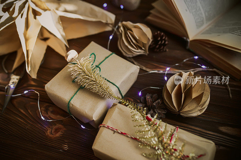 礼品盒用工艺纸制成，装饰有金色装饰。装饰圣诞树和蕨类叶子的礼物旁边手工圣诞树的装饰品