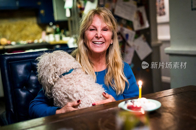 一个60多岁的成熟女人在家里吃着生日蛋糕，带着她的宠物狗过生日