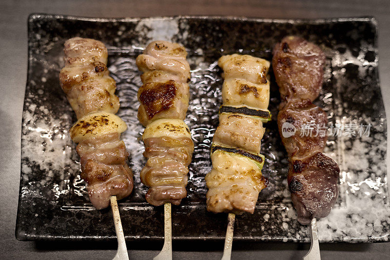 烤鸡肉串，日本传统的烤鸡肉。木桌上的烤盘和烤肉。烤烤鸡调味照片。日式烤鸡串。烹饪，餐厅，日本，东京。