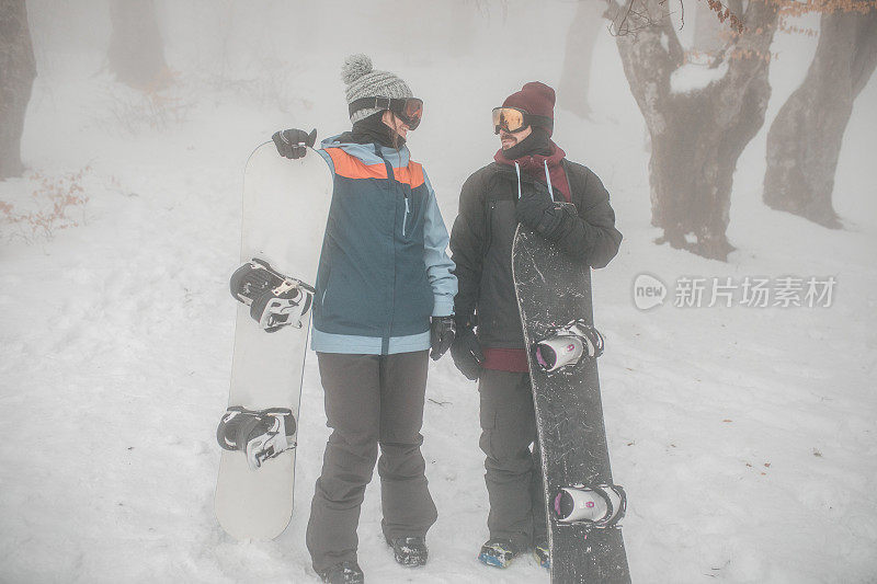 图为，手持滑雪板走向山顶的滑雪者们一边聊天，一边为滑雪做准备
