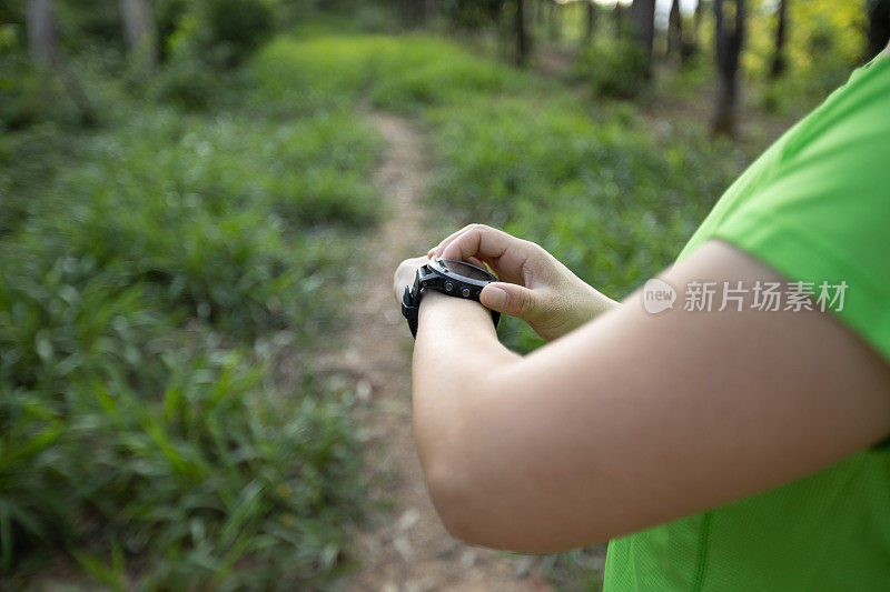 女越野跑运动员在森林里设置了运动手表
