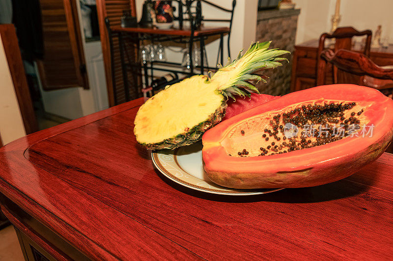 即食热带水果——半个木瓜和半个菠萝放在闪亮的红木桌上