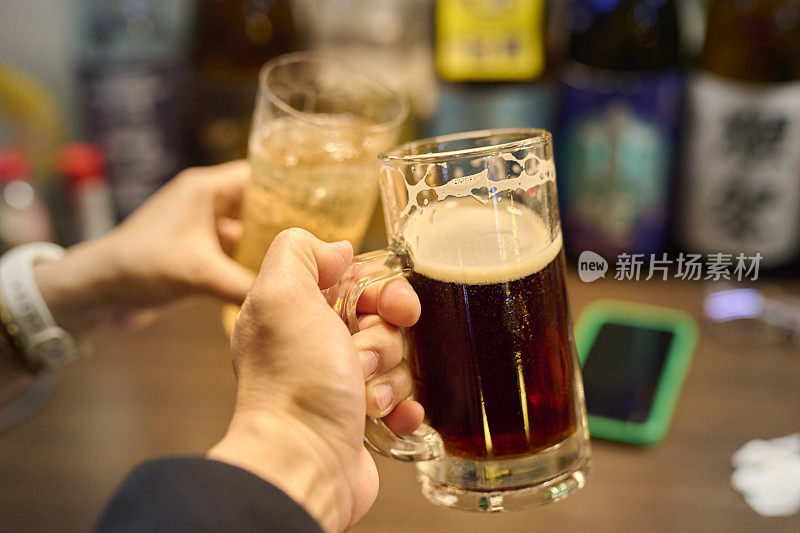 朋友们在日本酒吧餐厅喝啤酒。朋友快乐的概念，年轻人在凉爽的复古酒吧一起玩乐。