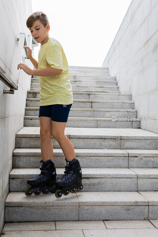 可爱的小男孩穿着旱冰鞋走下楼梯。儿童户外运动。