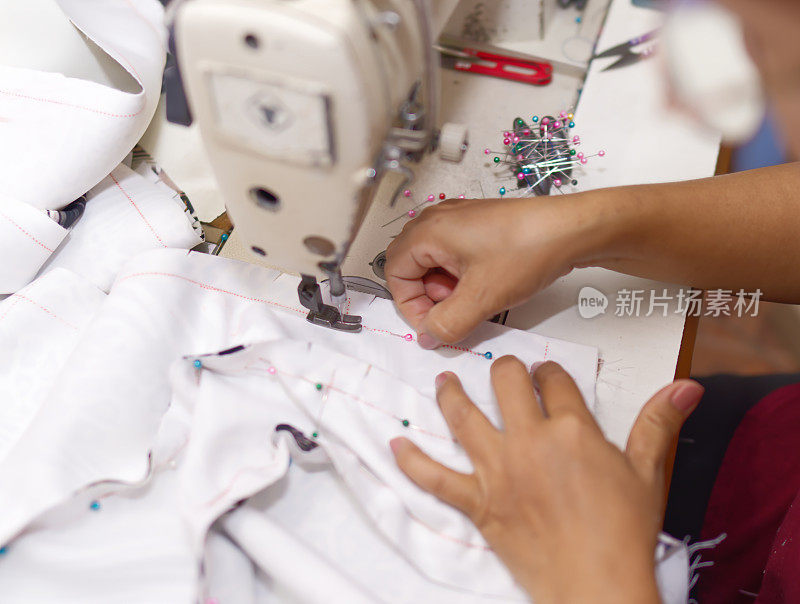 裁缝或设计师的手使用机器在螺柱上工作