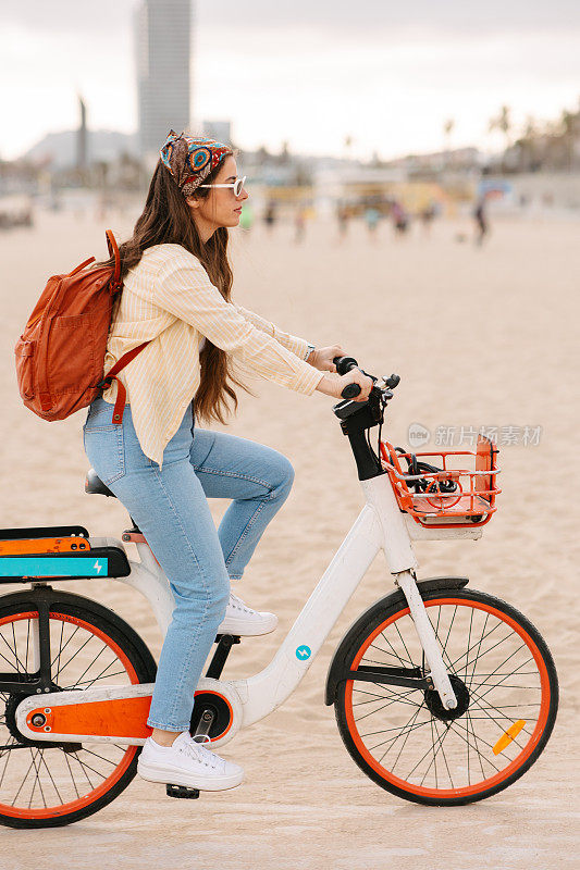在巴塞罗那的海滩上骑电动自行车的游客