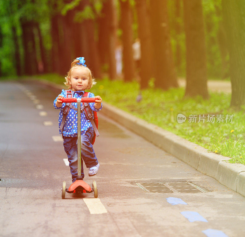 可爱的小女孩骑着滑板车在城里
