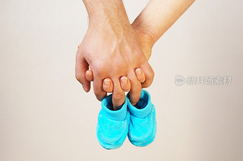 幸福年轻的父母手中握着未来孩子的婴儿鞋