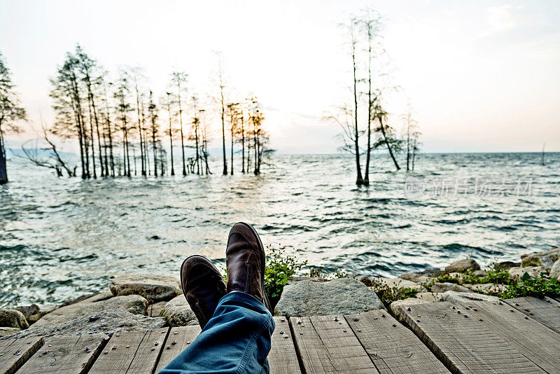 男人的脚在湖边穿鞋的特写