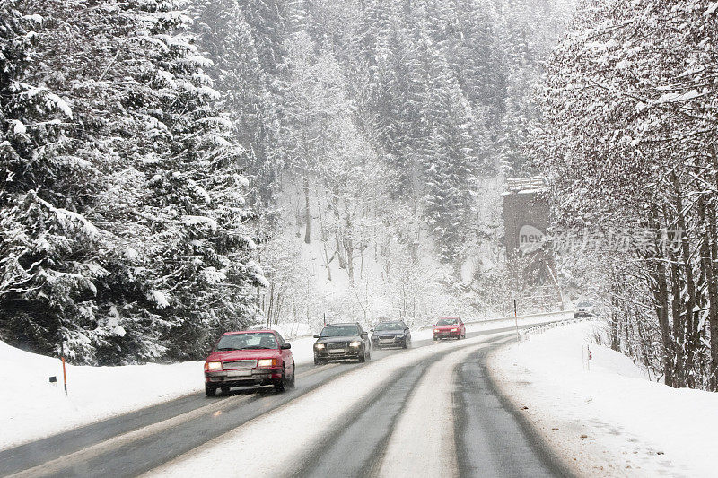 冬天，高速公路上的汽车穿过积雪的森林