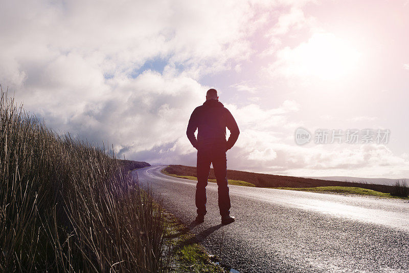 一个人站在开阔的乡村道路上