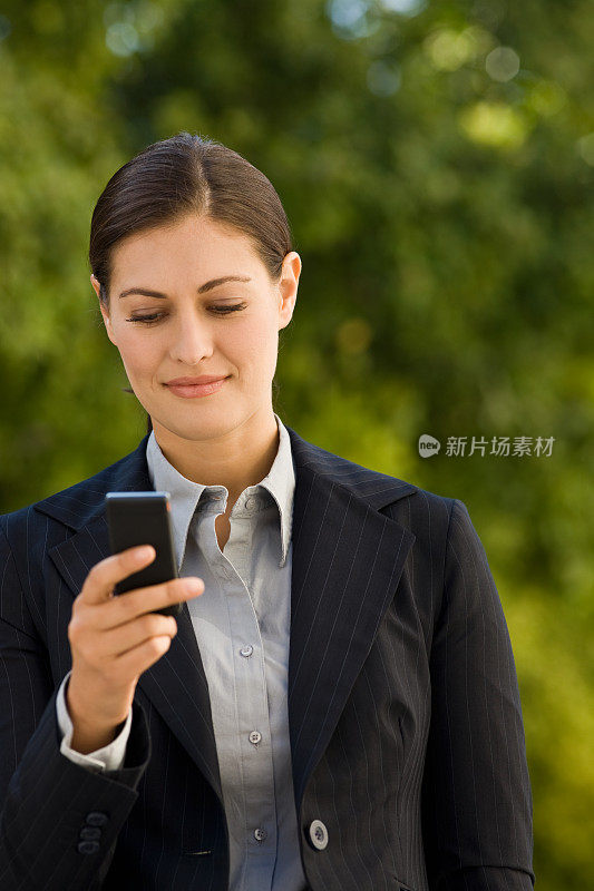 年轻的女商人用手机发短信