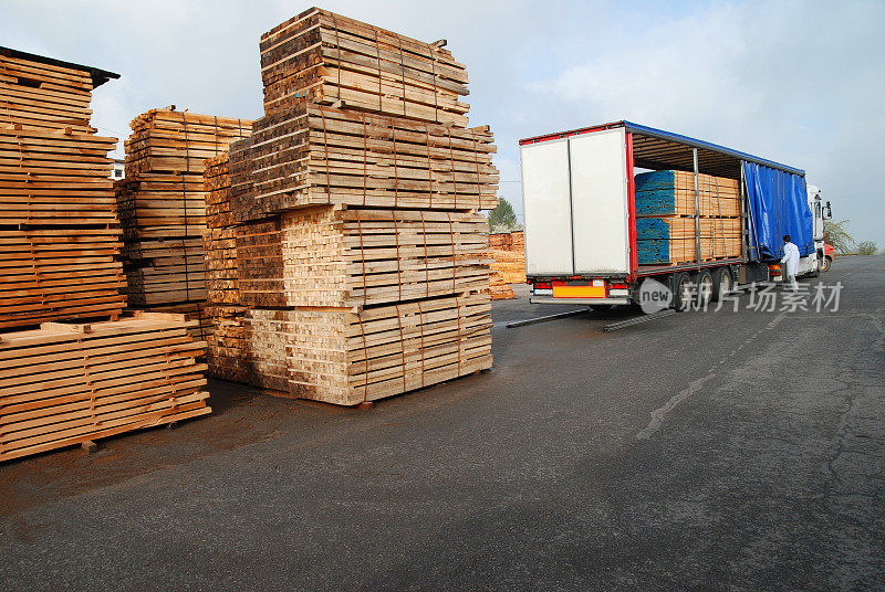 成堆的木材和满载的卡车