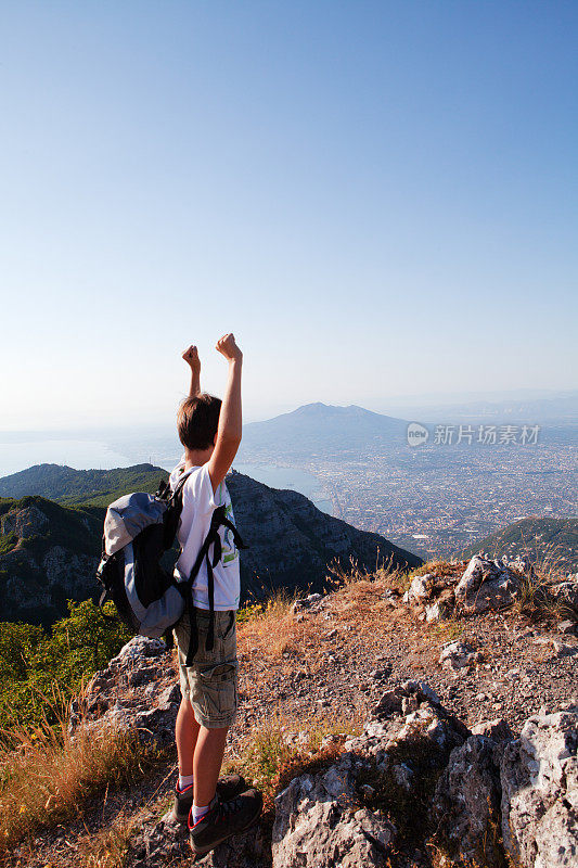 山顶上的男孩徒步旅行者，成功的概念