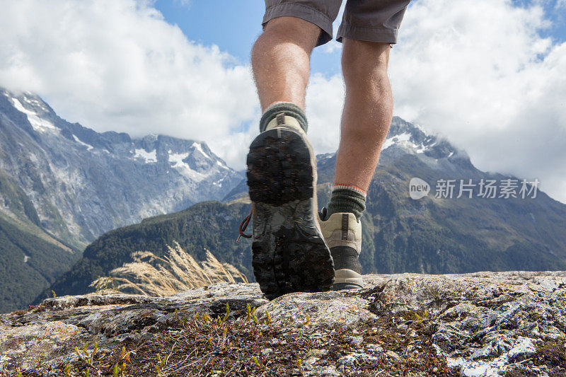 人的腿和登山靴站在岩石的山峰上
