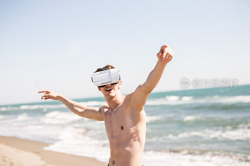 帅哥戴着VR眼镜在沙滩上冲浪。夏日理念，朋友，友谊，夏日乐趣，年轻人玩得开心