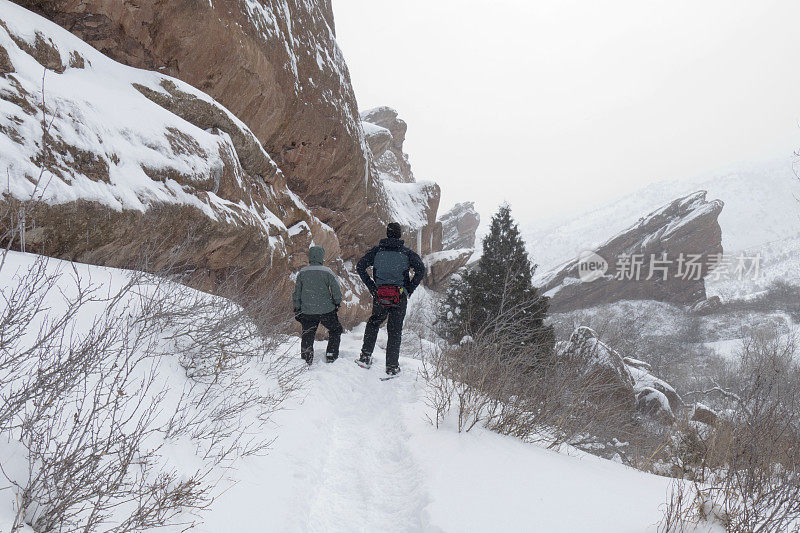 冬天，一对穿着雪鞋的夫妇在科罗拉多州莫里森的红岩公园徒步旅行