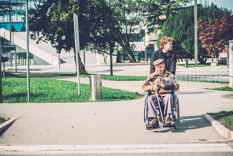 在轮椅上的老年残疾人和孙子在户外，欧洲