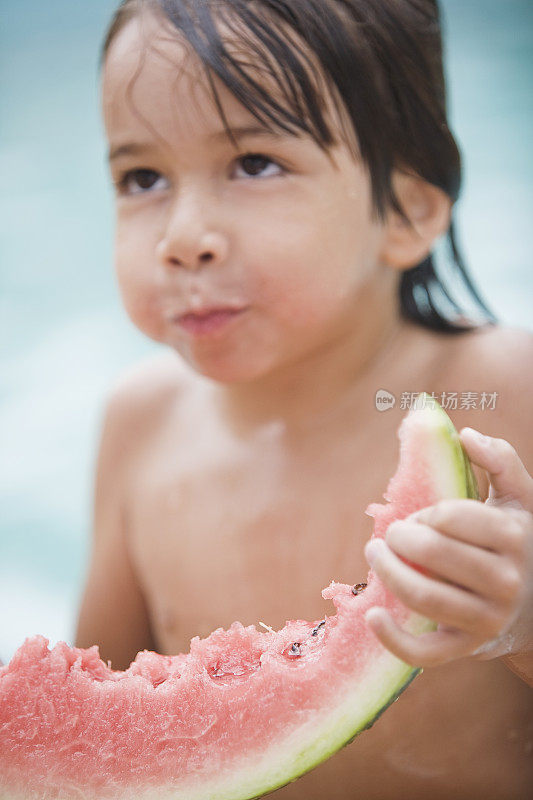 小男孩在泳池边吃西瓜