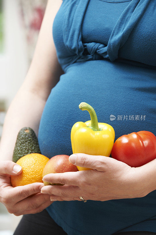 孕妇抱着水果和蔬菜的特写