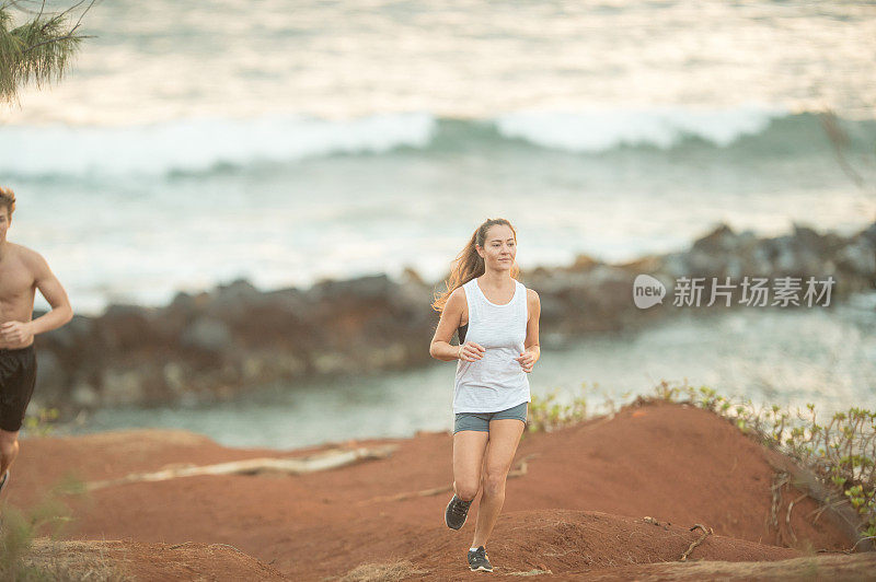 年轻的欧亚混血女子沿着夏威夷海滩奔跑