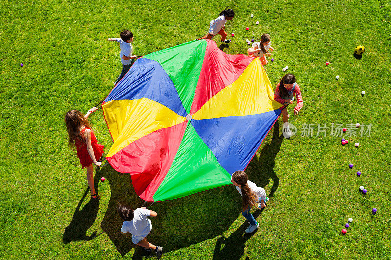 孩子们围着明亮的降落伞转着圈