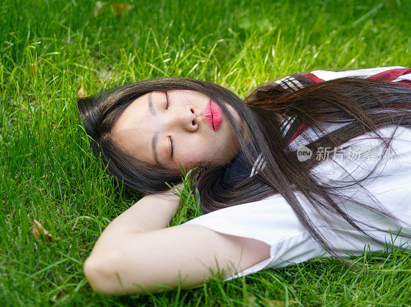 亚洲女学生在校服日本风格躺在草地上。