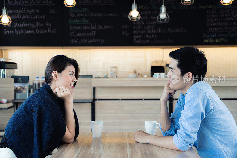 在咖啡馆约会。美丽的亚洲情侣坐在咖啡馆享受咖啡和谈话。爱和浪漫。
