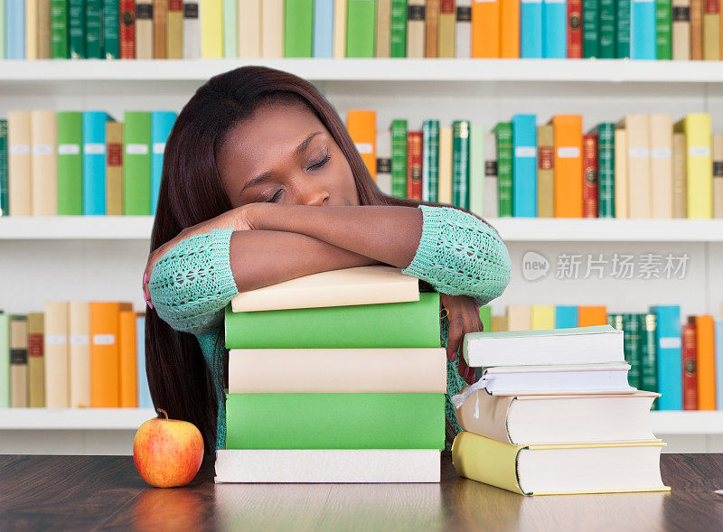 疲惫的大学生在图书馆的书上睡觉