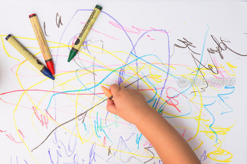 一只婴儿用彩色蜡笔画线条和形状的手。