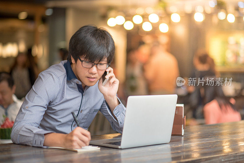 年轻的亚洲商人在咖啡馆用笔记本电脑工作