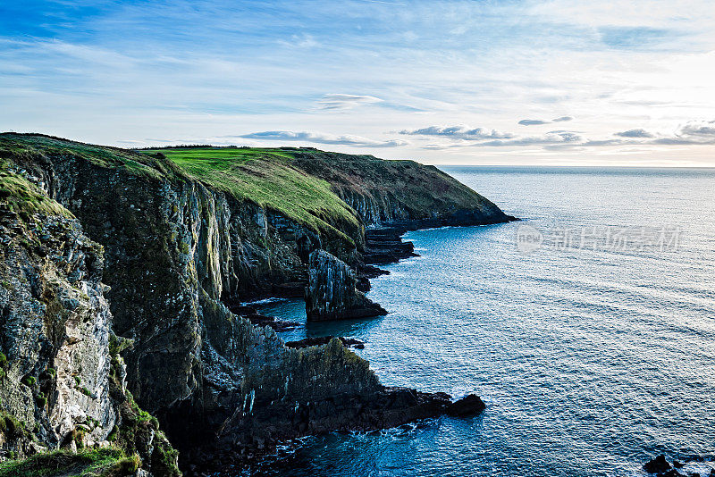 日落时爱尔兰海岸的悬崖和绿色山丘的风景。