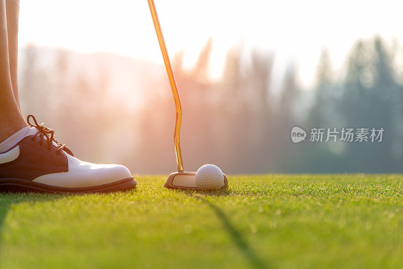 高尔夫球手亚洲女人把高尔夫球在绿色高尔夫在太阳日落的晚上时间。健康和生活方式的概念。