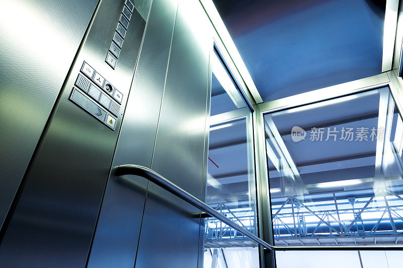 在现代建筑的金属和玻璃电梯内，闪亮的按钮和栏杆