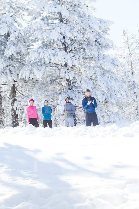 四个运动员在雪山上跑步休息