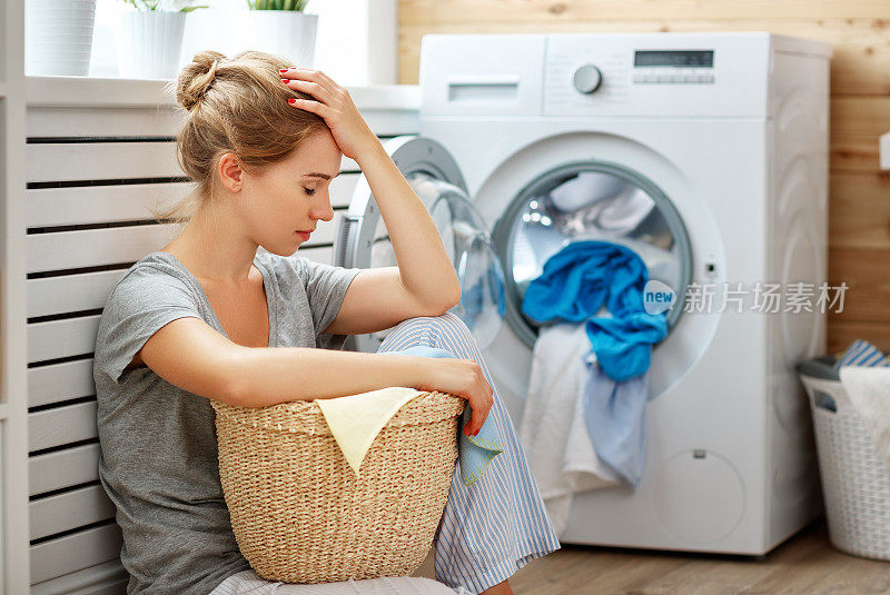 疲惫的家庭主妇在压力下睡在有洗衣机的洗衣房