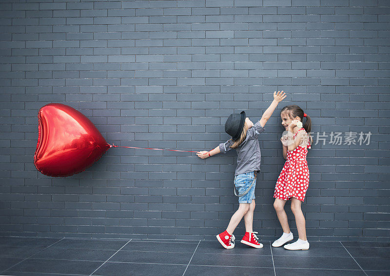 两个孩子拿着心形的气球