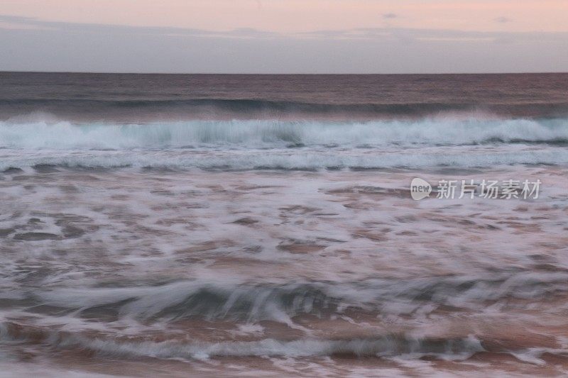 日出时海浪涌上海滩