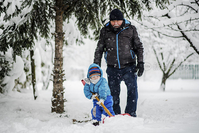 在冬天的一天，爷爷和孙子在清理积雪