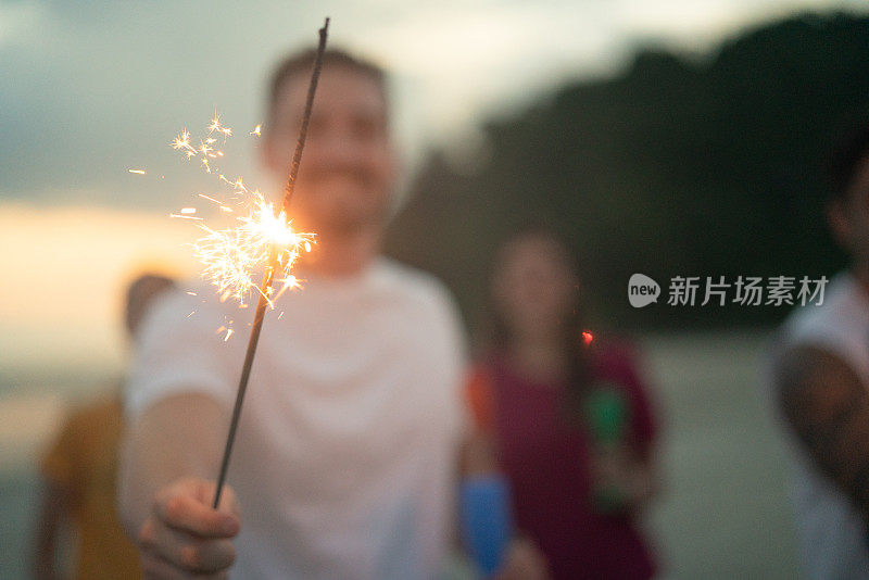 男人在海滩上拿着烟花庆祝新年