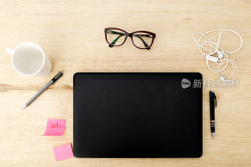 顶视图办公桌黑色笔记本电脑，智能手机，马克杯，眼镜和办公用品