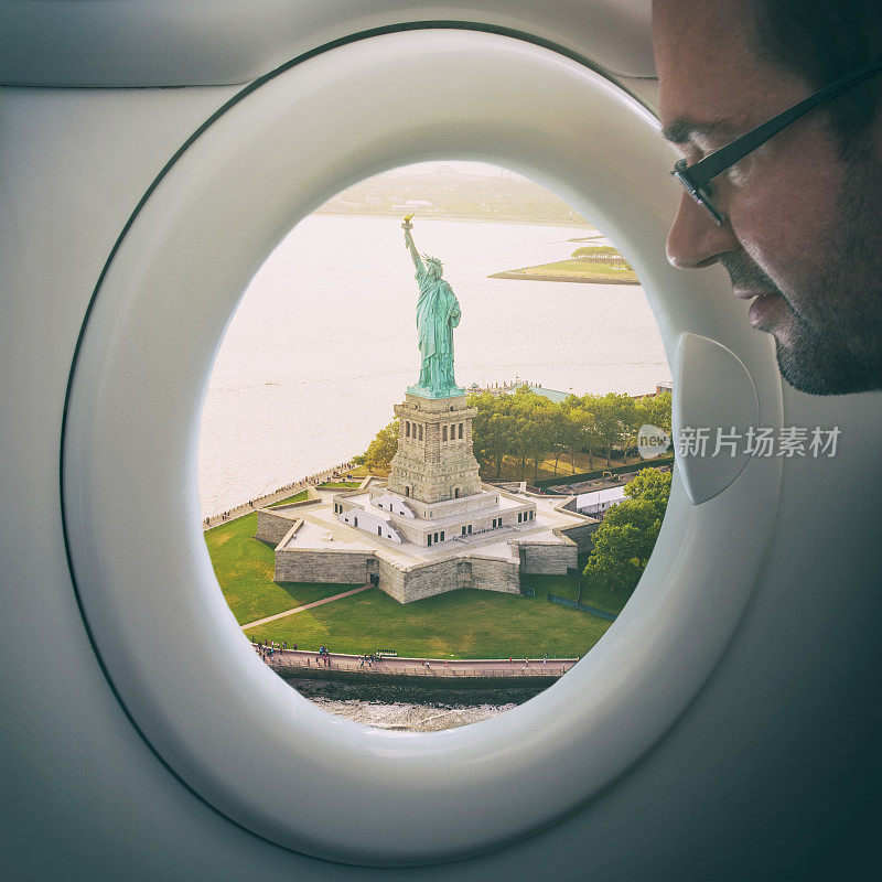 一个人从一架假的舷窗飞机上看着自由女神像