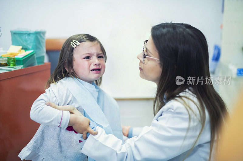 可爱的小女孩在牙医诊所里哭。