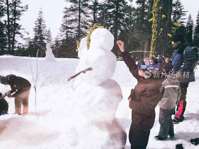 一家人和孩子们在特拉基堆雪人和玩雪，加州