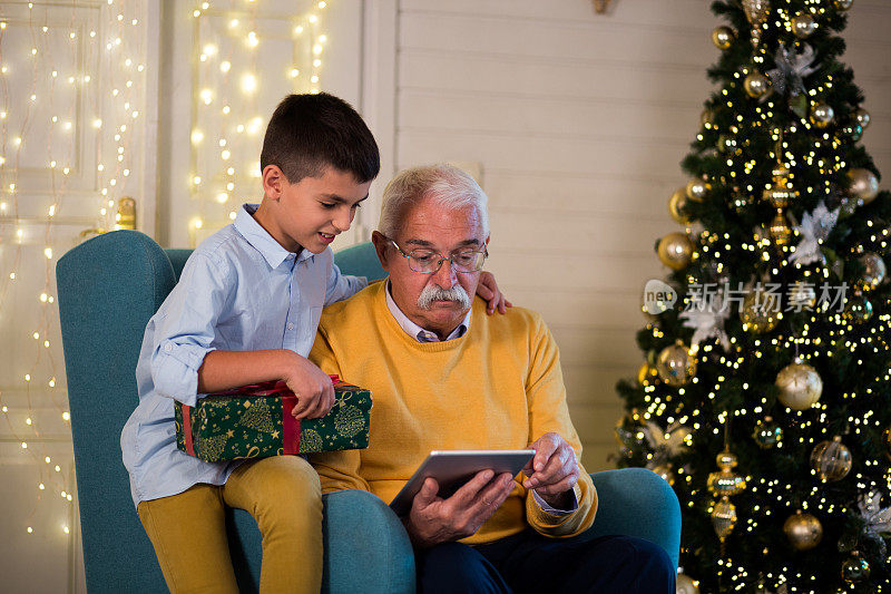 爷爷和孙子在平安夜使用平板电脑