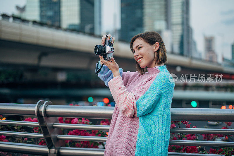 一位女士在城市里用相机拍照