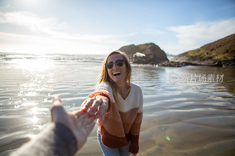 日落时分，在海滩上牵手玩耍的情侣