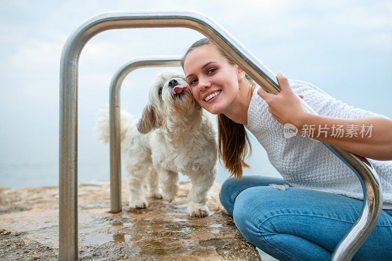 快乐的年轻女人和她的狗在海岸线