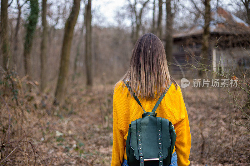 一位穿着随意的年轻女子正走在森林里